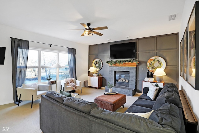 living room with ceiling fan, light carpet, and a fireplace