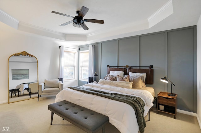 carpeted bedroom with a tray ceiling, crown molding, and ceiling fan