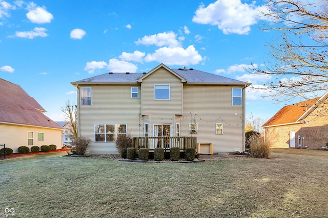 back of property featuring a wooden deck and a lawn