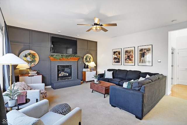 carpeted living room with ceiling fan and a brick fireplace