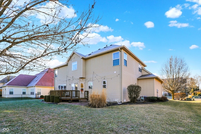 back of house featuring a wooden deck and a lawn