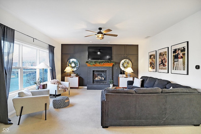 carpeted living room featuring ceiling fan and a fireplace