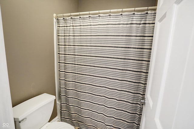 bathroom featuring a shower with shower curtain and toilet