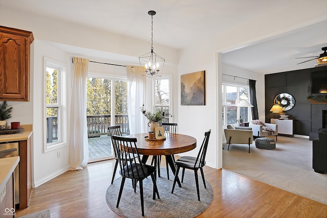 dining space featuring ceiling fan, a fireplace, and light hardwood / wood-style floors