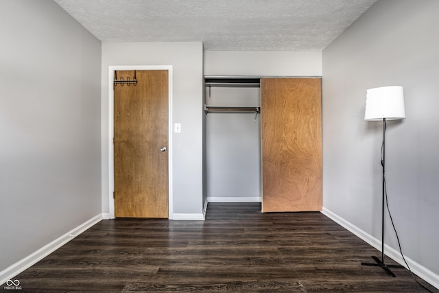 unfurnished bedroom featuring a textured ceiling, dark hardwood / wood-style flooring, and a closet