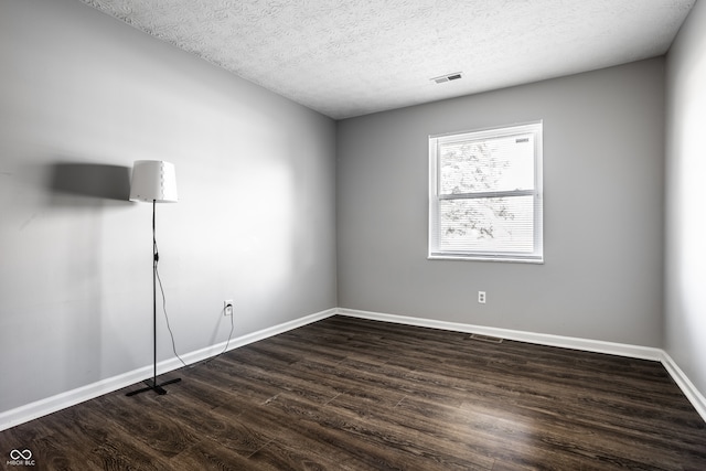 empty room featuring dark wood-type flooring and a textured ceiling