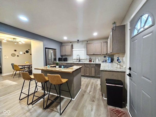 kitchen featuring a kitchen bar, butcher block countertops, a center island, light hardwood / wood-style flooring, and appliances with stainless steel finishes