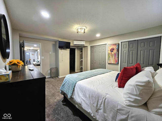 carpeted bedroom with a wall mounted air conditioner and multiple closets