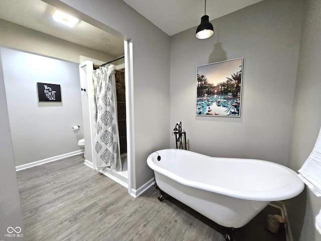 bathroom featuring shower with separate bathtub, hardwood / wood-style floors, and toilet