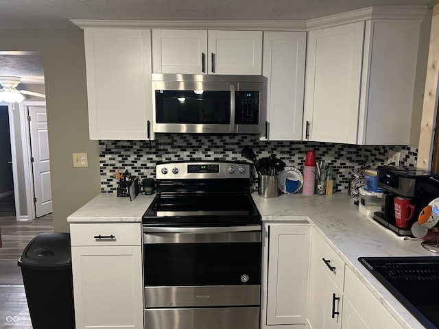 kitchen with white cabinetry, tasteful backsplash, light stone counters, dark hardwood / wood-style flooring, and stainless steel appliances