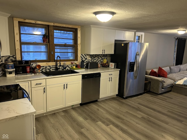 kitchen with appliances with stainless steel finishes, dark hardwood / wood-style floors, white cabinetry, sink, and decorative backsplash