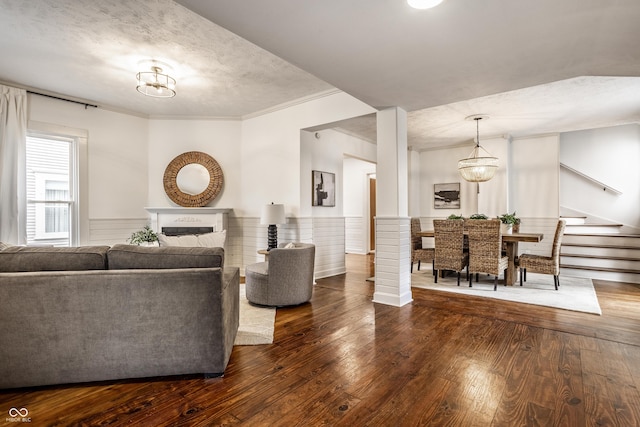 living room featuring ornamental molding, dark wood-type flooring, a textured ceiling, and an inviting chandelier