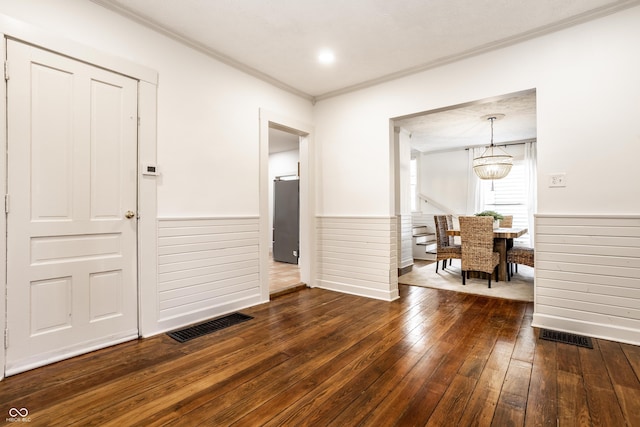 dining space featuring dark wood-type flooring, crown molding, and an inviting chandelier