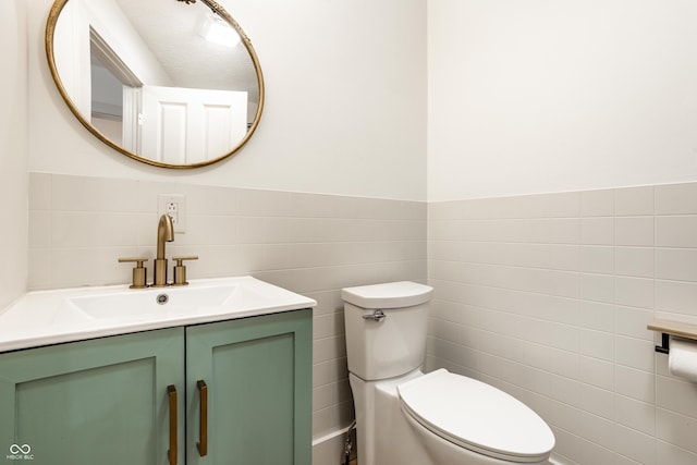 bathroom featuring vanity, tile walls, and toilet