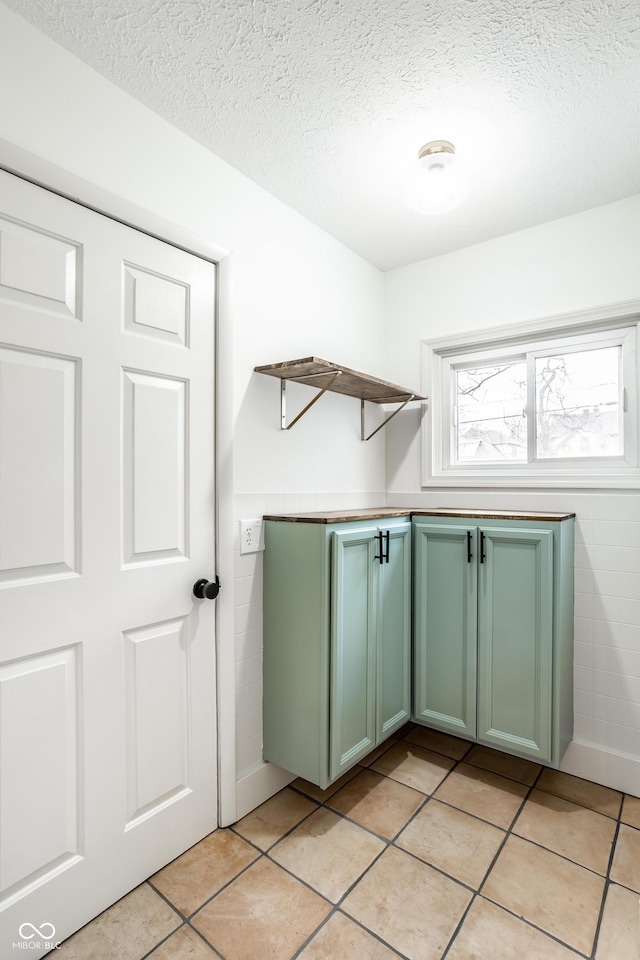 laundry area with light tile patterned flooring, a textured ceiling, and tile walls