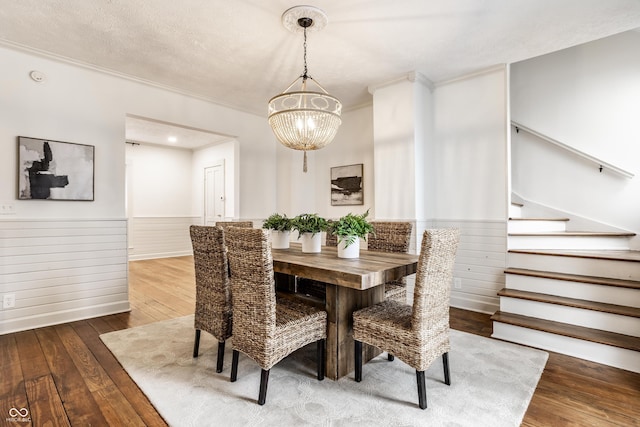 dining space featuring ornamental molding, dark wood-type flooring, a notable chandelier, and a textured ceiling