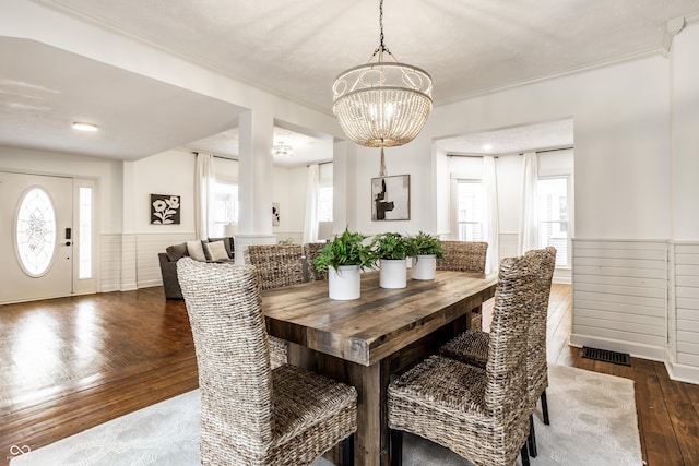 dining room featuring ornamental molding, dark hardwood / wood-style floors, a wealth of natural light, and a chandelier