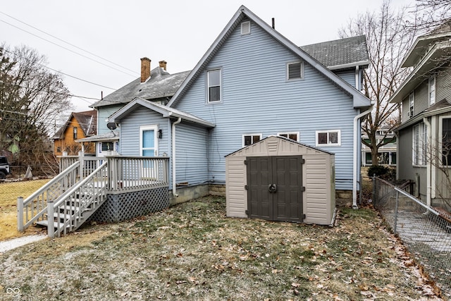 back of house featuring a wooden deck, a lawn, and a shed