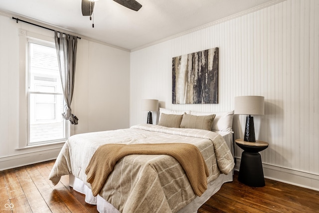 bedroom featuring dark wood-type flooring, ornamental molding, and ceiling fan