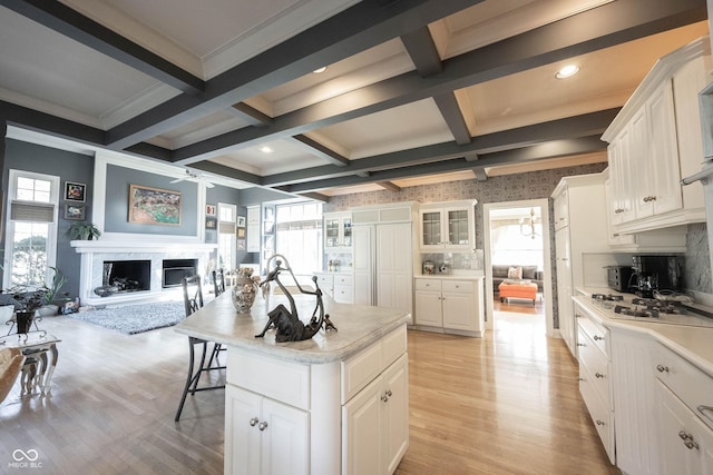 kitchen with a healthy amount of sunlight, a fireplace with raised hearth, and beam ceiling