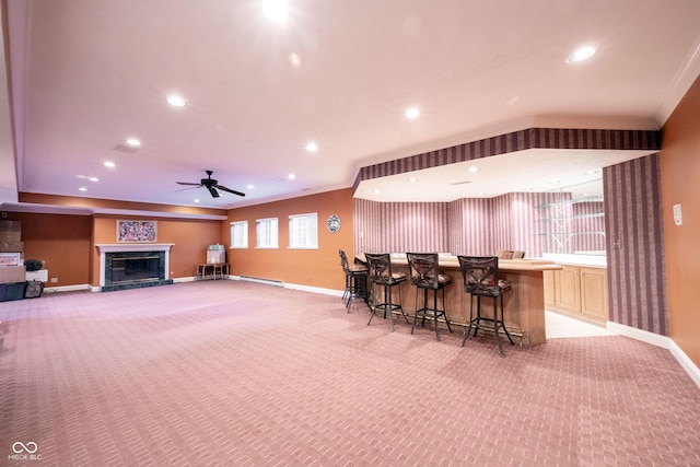 interior space with a baseboard heating unit, bar area, light colored carpet, and baseboards