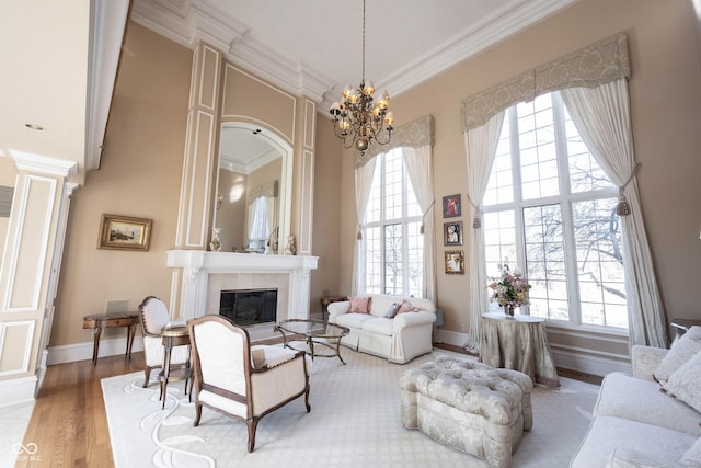 living area featuring a large fireplace, ornamental molding, wood finished floors, and a towering ceiling