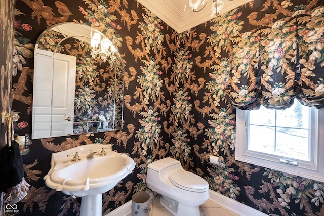 half bath with crown molding, toilet, a sink, tile patterned flooring, and baseboards