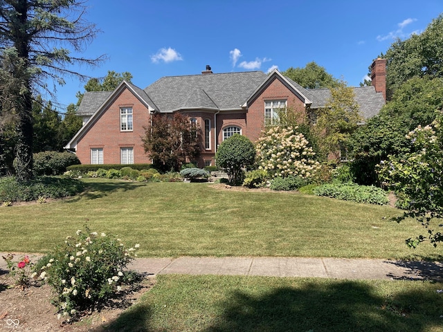 view of front of house featuring a front yard, brick siding, and a chimney