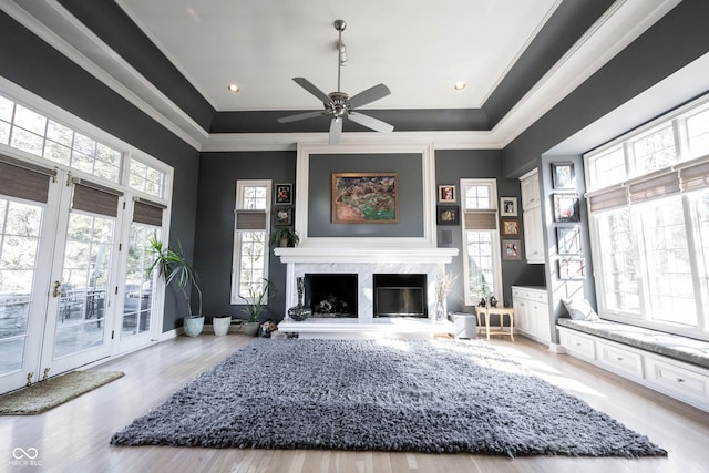 living room with baseboards, a premium fireplace, wood finished floors, and crown molding