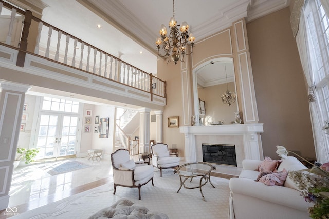 living area with french doors, a fireplace, a towering ceiling, and crown molding