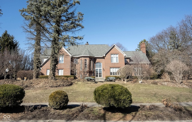 view of front of house with a chimney, a front lawn, and brick siding