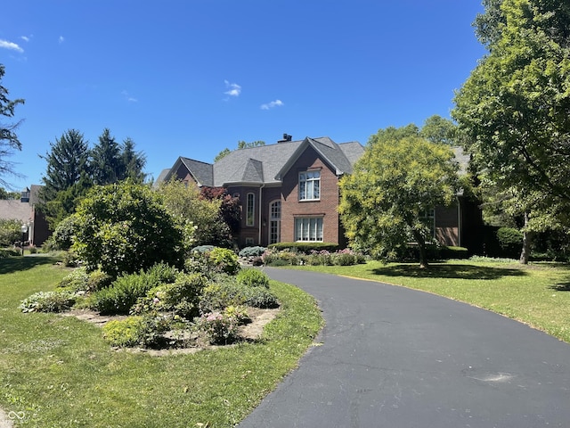 view of front facade featuring driveway, brick siding, and a front yard