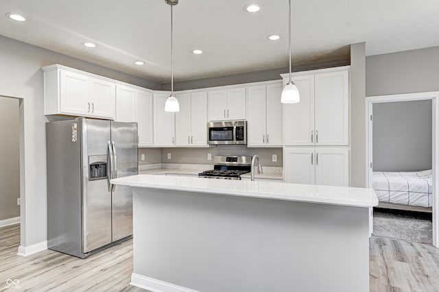 kitchen featuring appliances with stainless steel finishes, hanging light fixtures, and a center island with sink