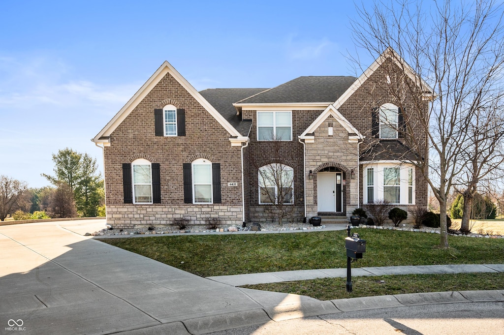 view of front of home with brick siding, stone siding, driveway, and a front lawn