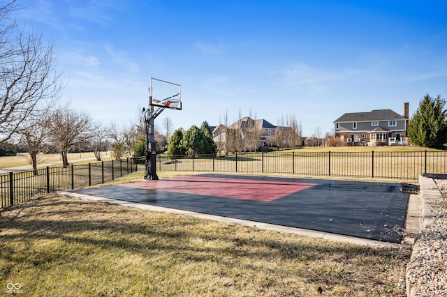 view of basketball court with a lawn, basketball court, and fence