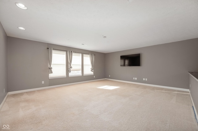 spare room with recessed lighting, light colored carpet, baseboards, and a textured ceiling