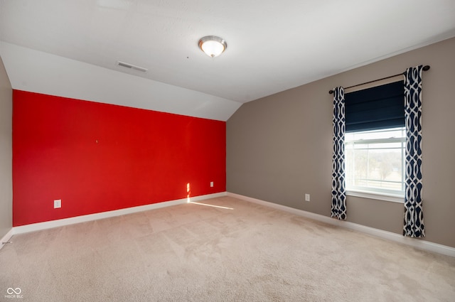 carpeted empty room with lofted ceiling, visible vents, and baseboards