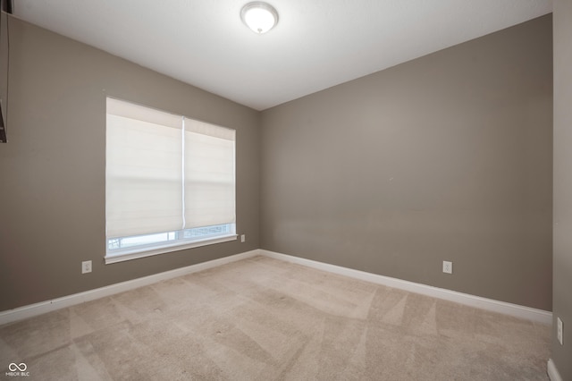 carpeted empty room featuring baseboards