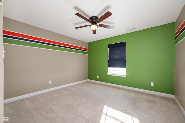 carpeted spare room featuring visible vents, a ceiling fan, and baseboards