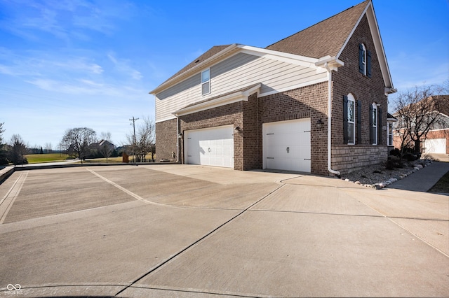 view of side of property featuring a garage, brick siding, and driveway