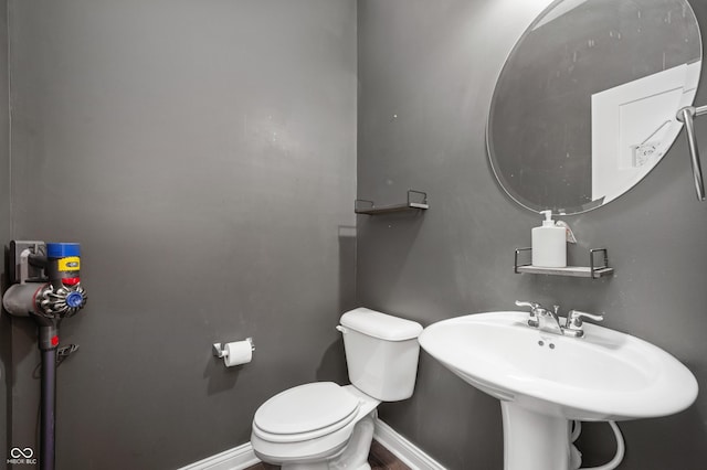 half bathroom featuring baseboards and toilet