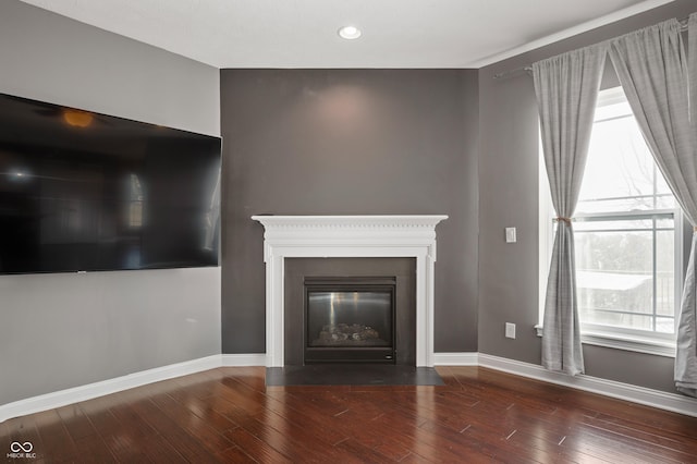 unfurnished living room featuring hardwood / wood-style flooring, a fireplace with flush hearth, recessed lighting, and baseboards