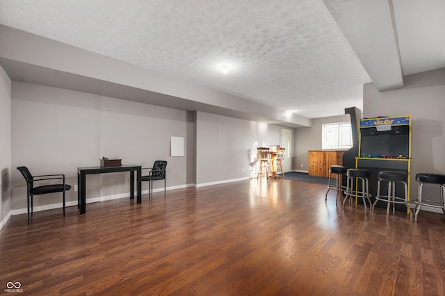 interior space featuring a textured ceiling, a bar, baseboards, and wood finished floors