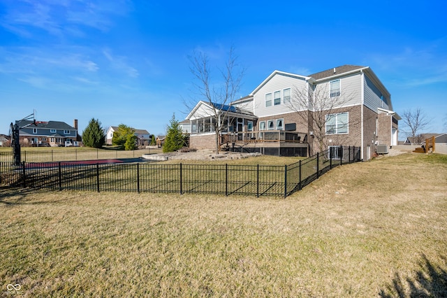 back of property with central air condition unit, a lawn, brick siding, and fence