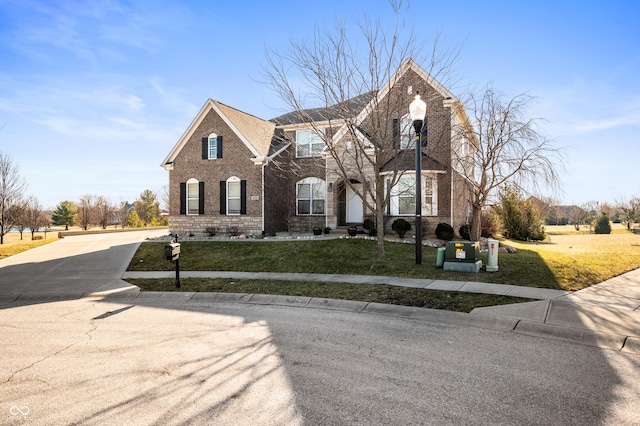 view of front of house featuring a front yard, brick siding, and driveway