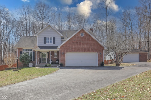 traditional-style house featuring a front lawn, driveway, fence, an attached garage, and brick siding