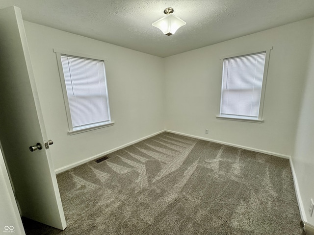 carpeted empty room with a textured ceiling