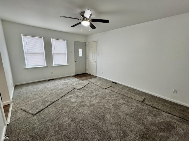 spare room with ceiling fan and dark carpet