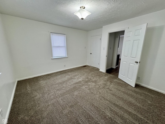 unfurnished bedroom featuring a textured ceiling and dark colored carpet