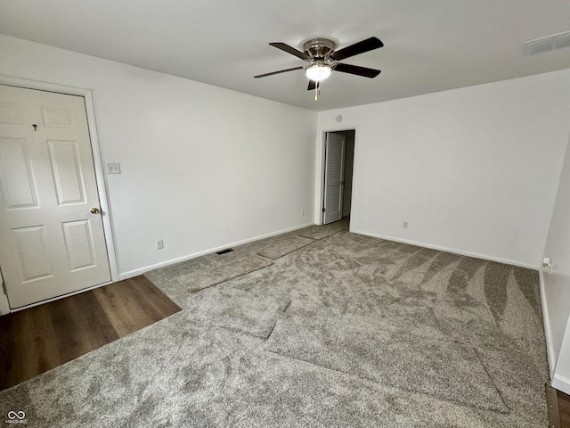 empty room with ceiling fan and dark carpet